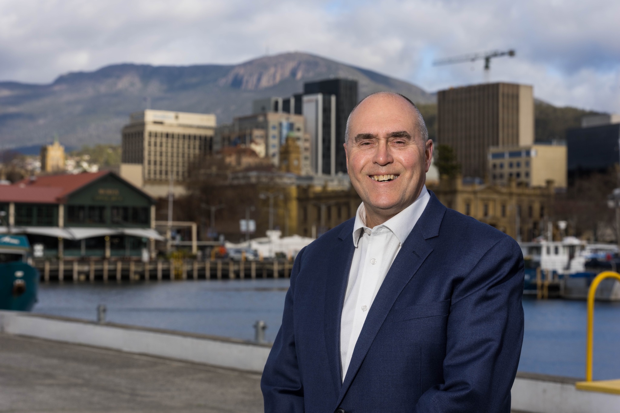 Harvey Lennon on Hobart's waterfront, with the city and kunanyi / Mount Wellington behind him
